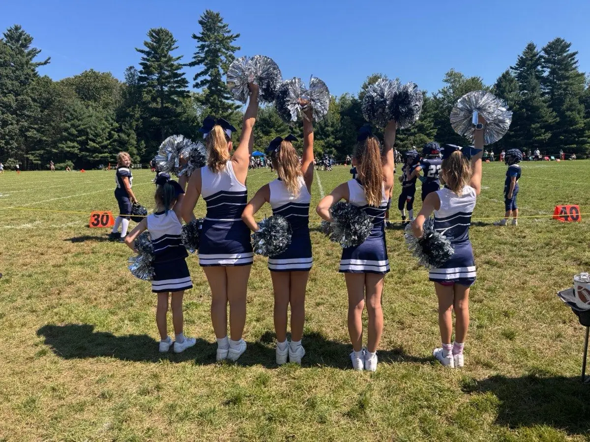 Seahawks cheerleaders holding pom-poms high on the sideline